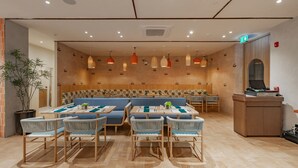 Ein Restaurant mit einer langen Theke, verschiedenen Sitzmöglichkeiten, darunter eine große, blaue Couch und mehrere Tische mit Stühlen.