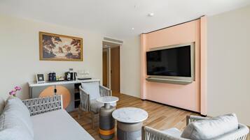 Un salon moderne avec un canapé, des fauteuils, un coin café et un téléviseur fixé au mur.