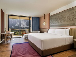 A hotel room with a large bed, a balcony with a view, a dining area, and a decorative wall. - Grand Mercure Krabi Aonang (Krabi)