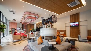 Eine moderne Lobby mit einer zentralen Sitzgruppe, einer Treppe und einem an der Wand montierten Fernseher.
