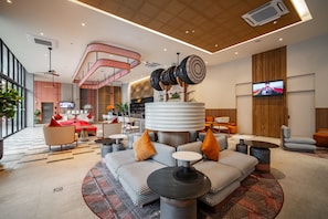 A modern lobby with a central seating area, a staircase, and a TV mounted on the wall. - Grand Mercure Krabi Aonang (Krabi)