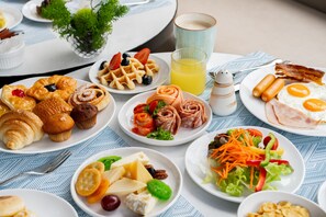Aamiainen sisältää monipuolisen valikoiman leivonnaisia, hedelmiä, vihanneksia sekä lasillisen appelsiinimehua.