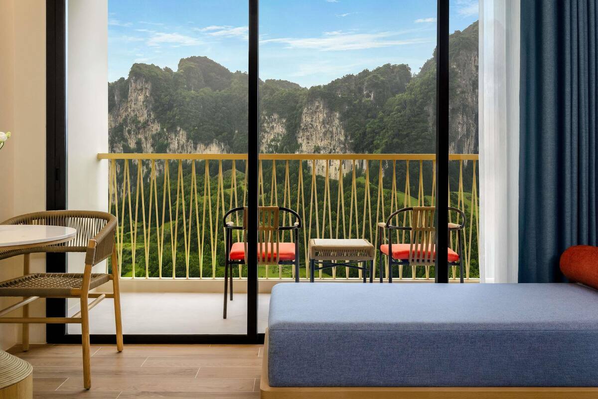 Ein Balkon mit Blick auf eine Berglandschaft, ein Bett und zwei Sessel.