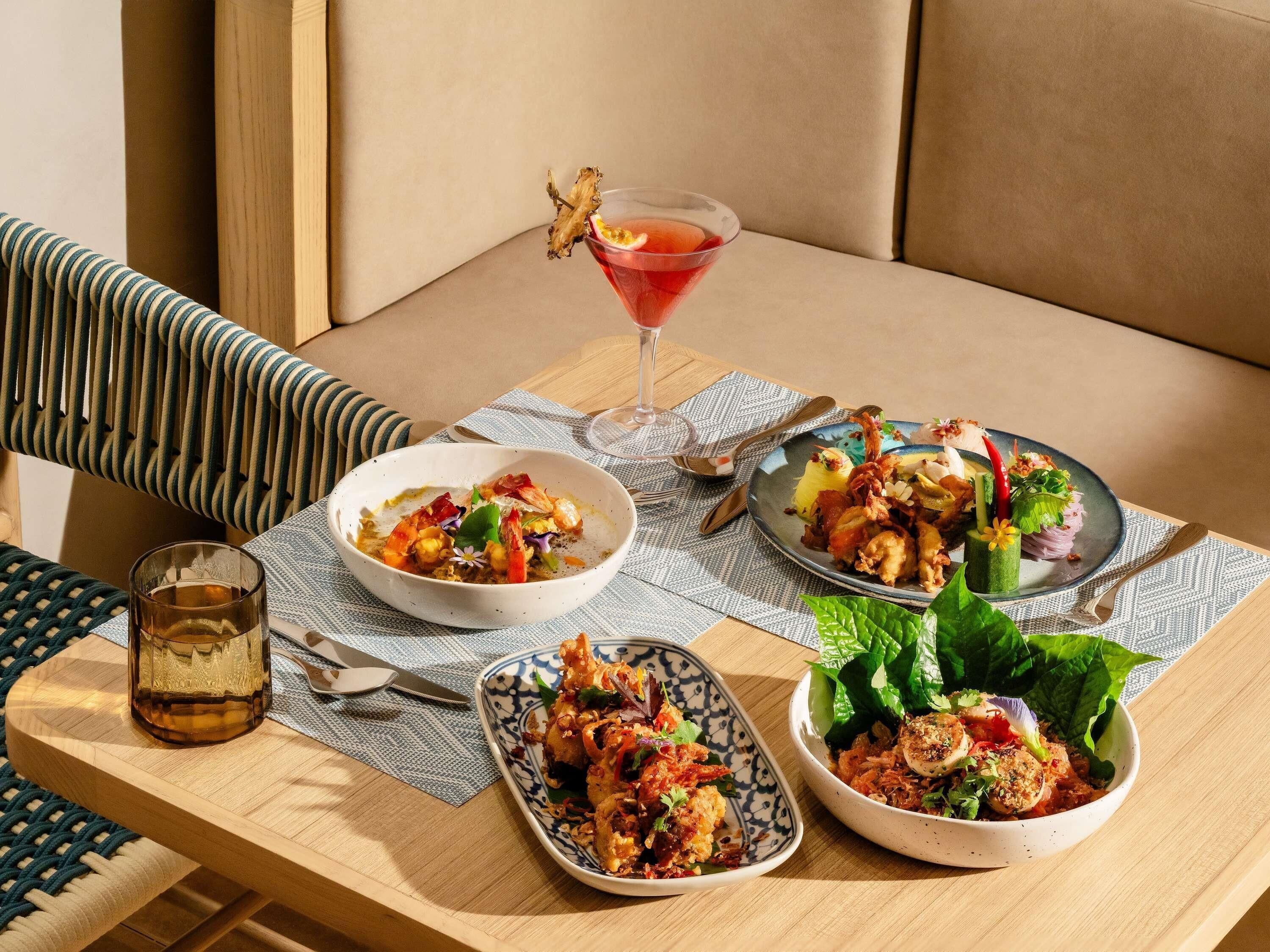 Una mesa de comedor con tres recipientes de comida, una copa de martini y una jarra de cerveza.