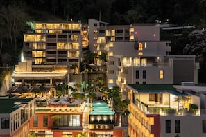 Un hôtel à plusieurs étages doté de balcons, d’un bar sur le toit et d’une piscine.