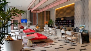 Eine moderne Hotelhalle mit Sitzbereichen, einem Empfangsschalter und einem Fernsehbildschirm.