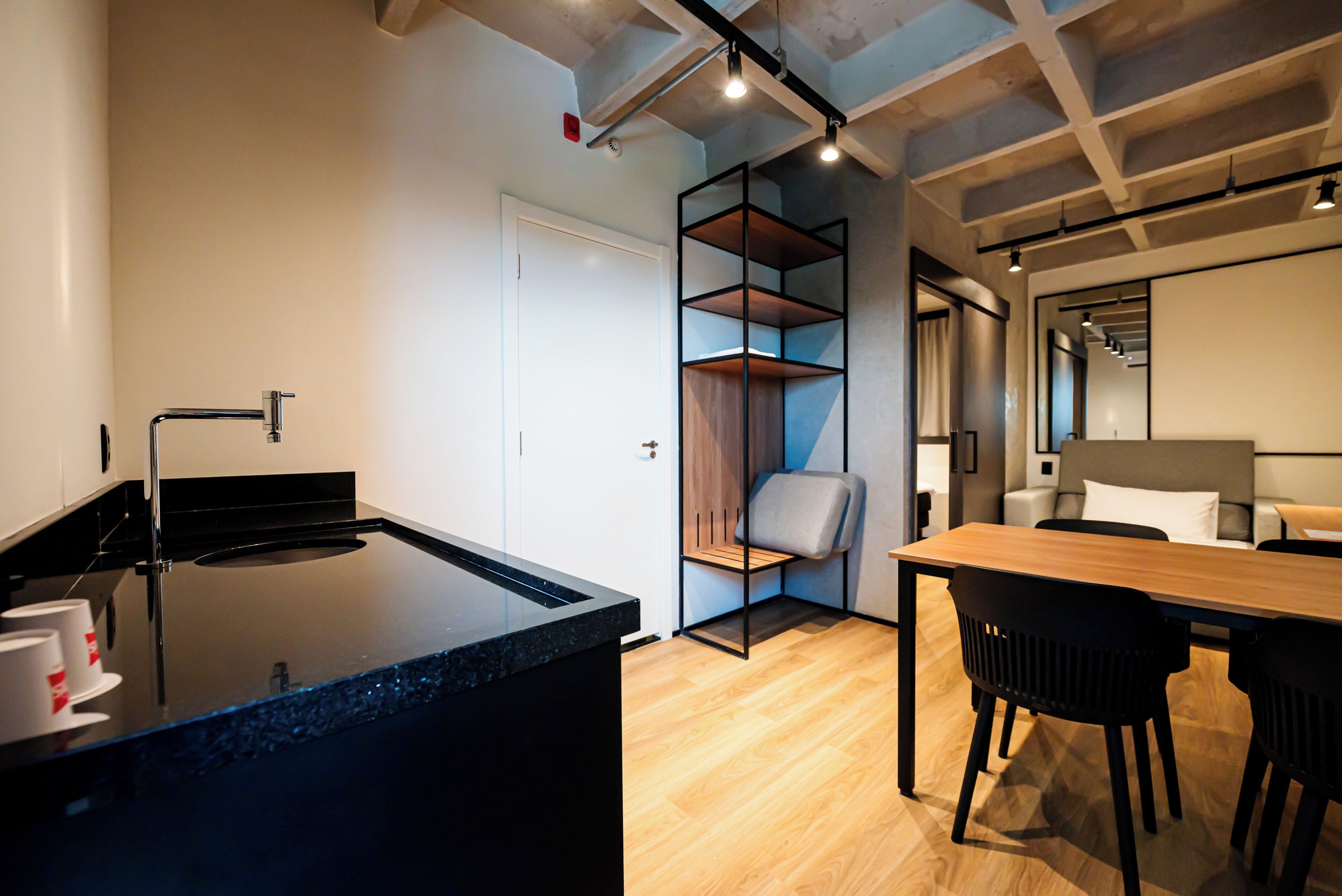 Una cocina moderna con encimera negra, una mesa de comedor de madera y sillas negras.