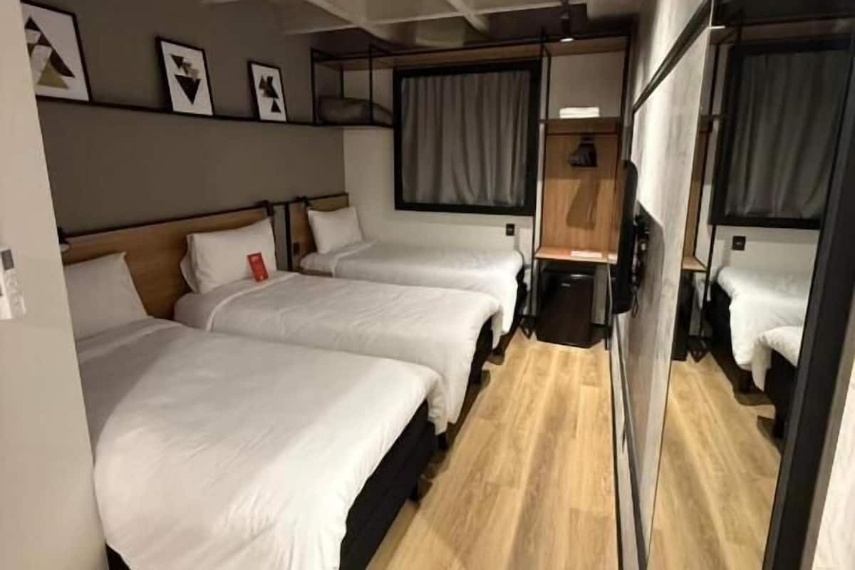 A compact room with two beds, a small table, and a mirror.