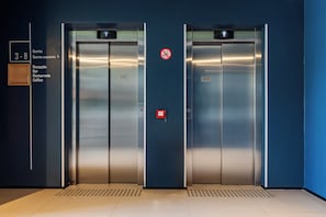 Two elevator doors with a no-smoking sign, a floor indicator, and a sign listing amenities like a bar and restaurant. - ibis Pelotas (Pelotas)