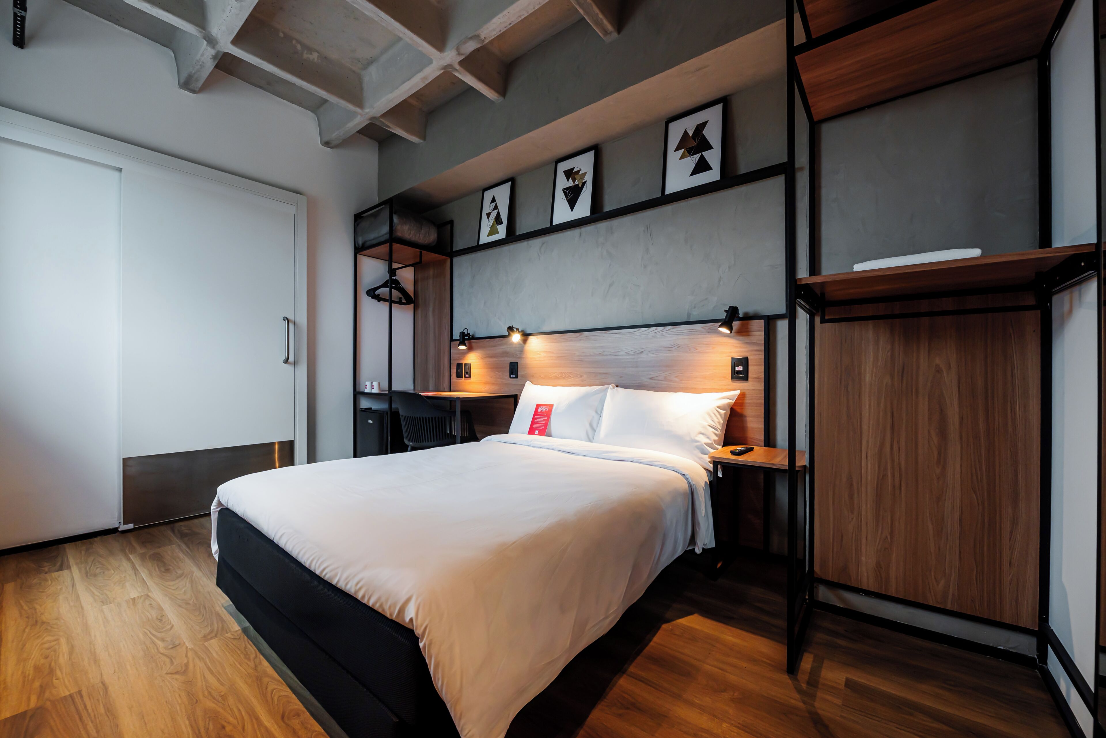 Un dormitorio moderno con una cama grande, suelo de madera, un escritorio y un armario.