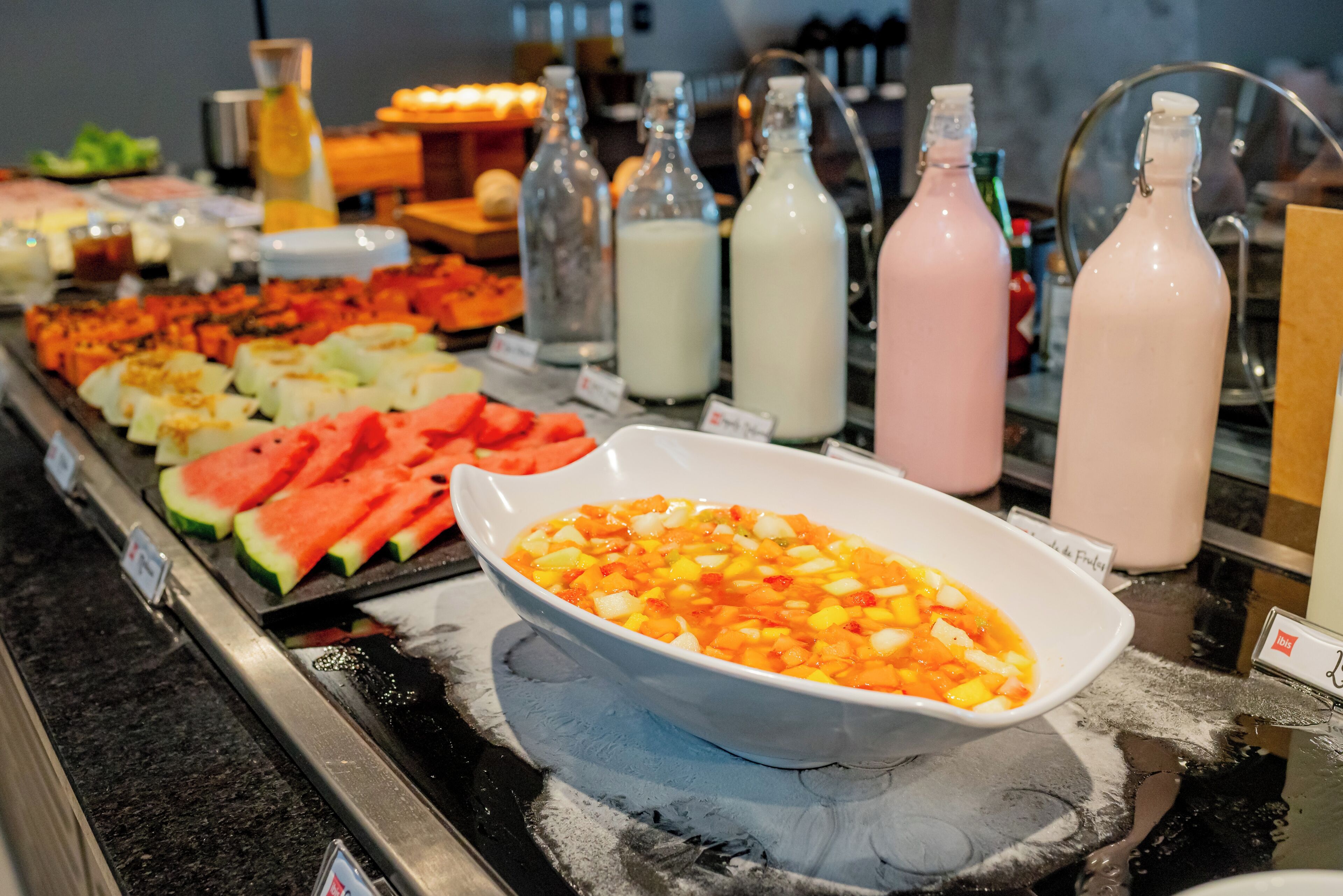 A buffet with various fruits, vegetables, and beverages.