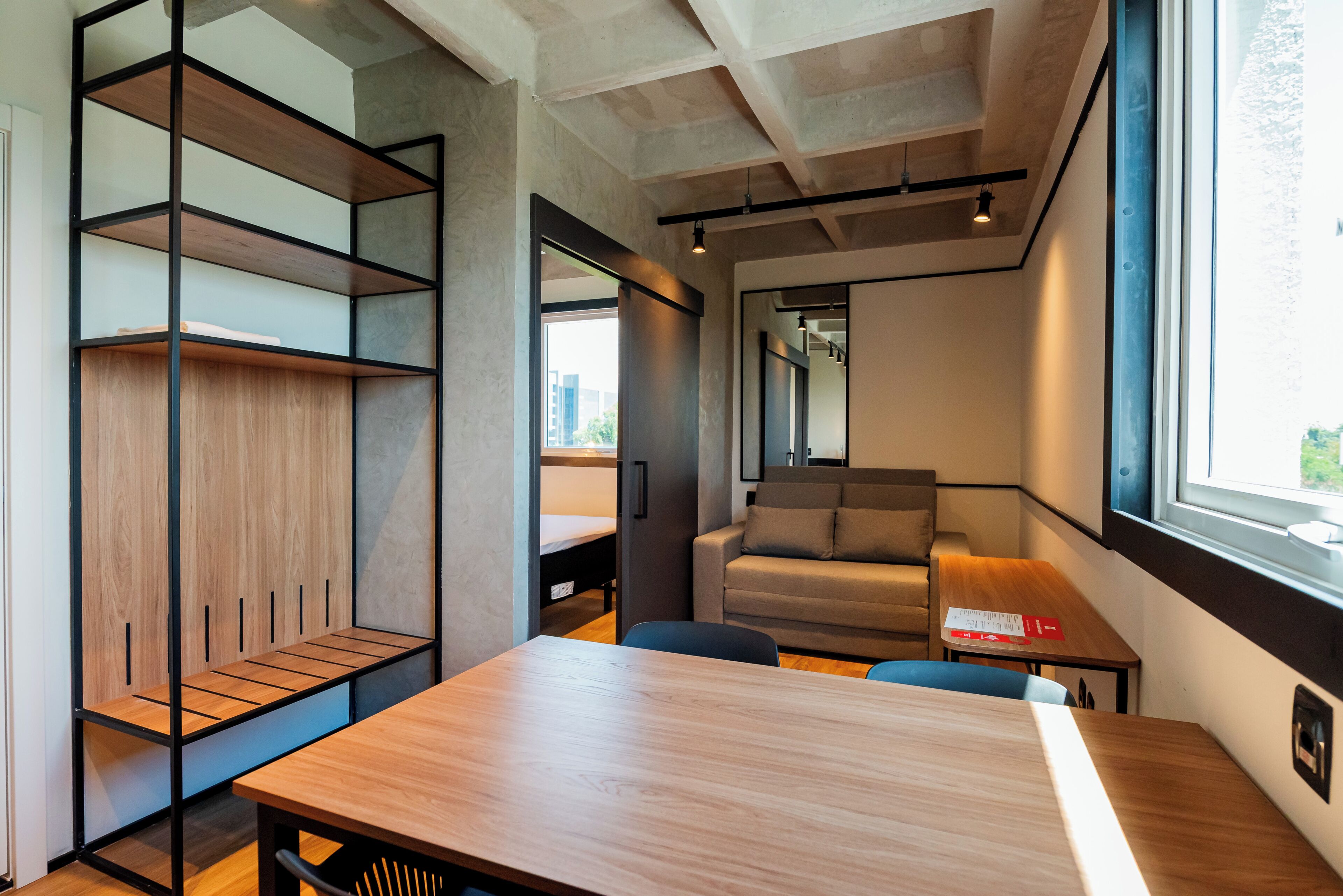 Een moderne, compacte kamer met een houten tafel, een slaapbank en een stapelbed.