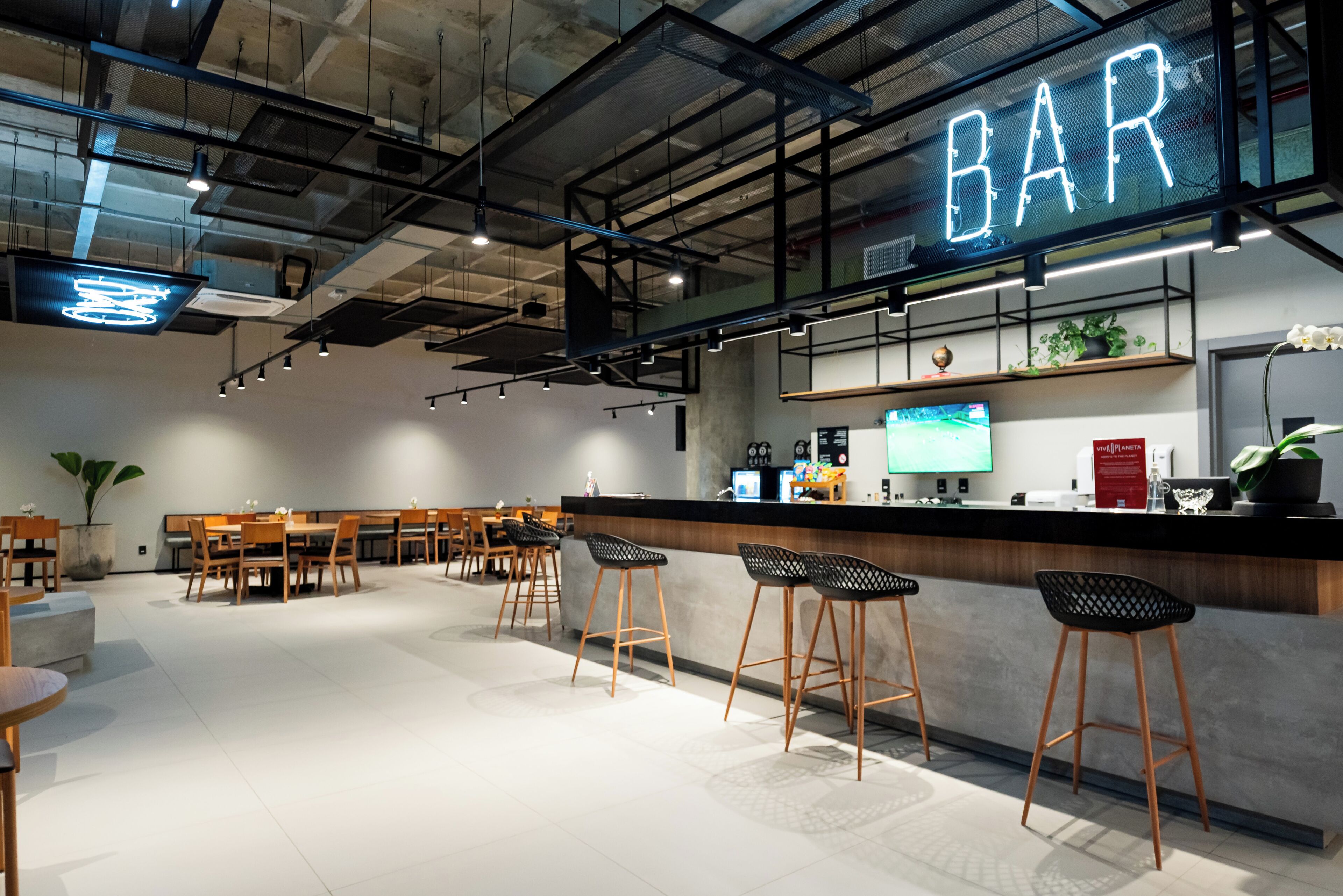 Eine moderne Bar mit Neonreklame, Holzsesseln und einer Theke mit Fernseher.