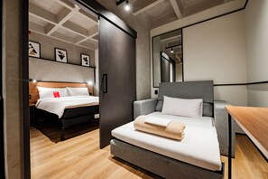 Ein modernes Hotelzimmer mit einem Bett, einer Couch, einem Schreibtisch und einem großen Spiegel.
