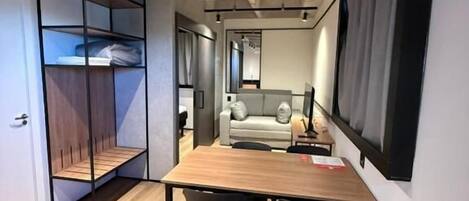 A compact room with a wooden table, two chairs, a sofa, and a built-in shelving unit.