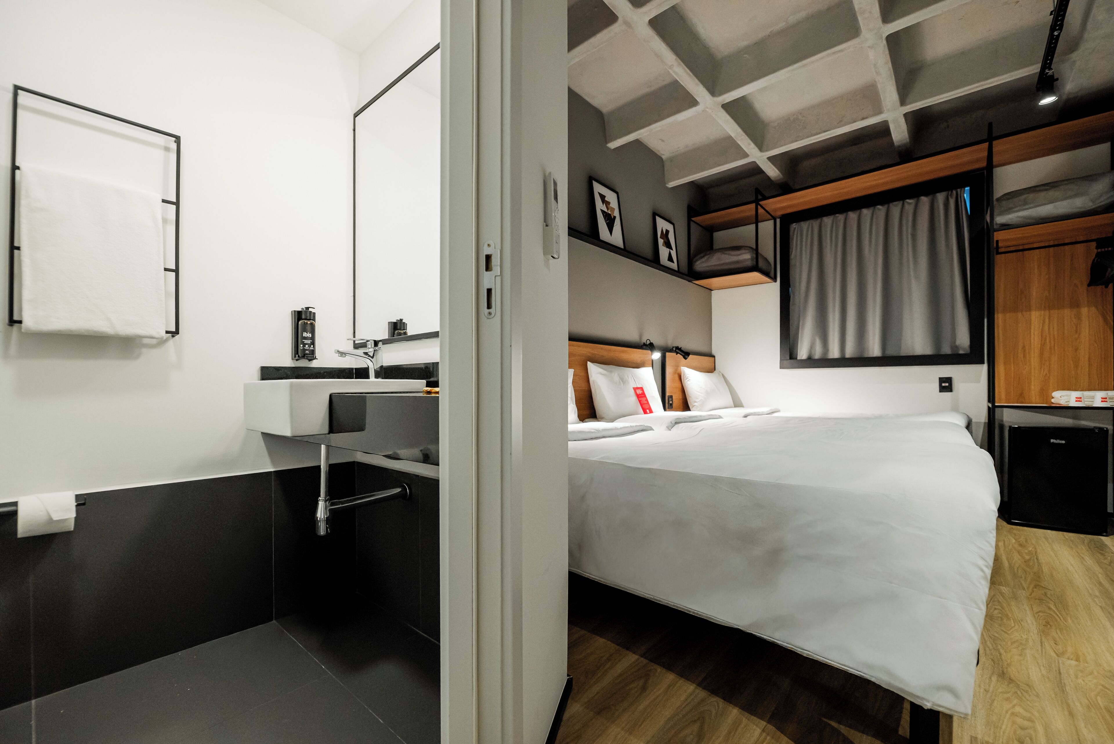 Una habitación de hotel moderna con una cama, un baño con lavamanos y ducha.
