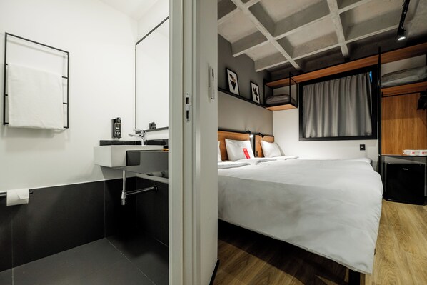 Ein modernes Hotelzimmer mit einem Bett, einem Badezimmer mit Waschbecken und einer Dusche.