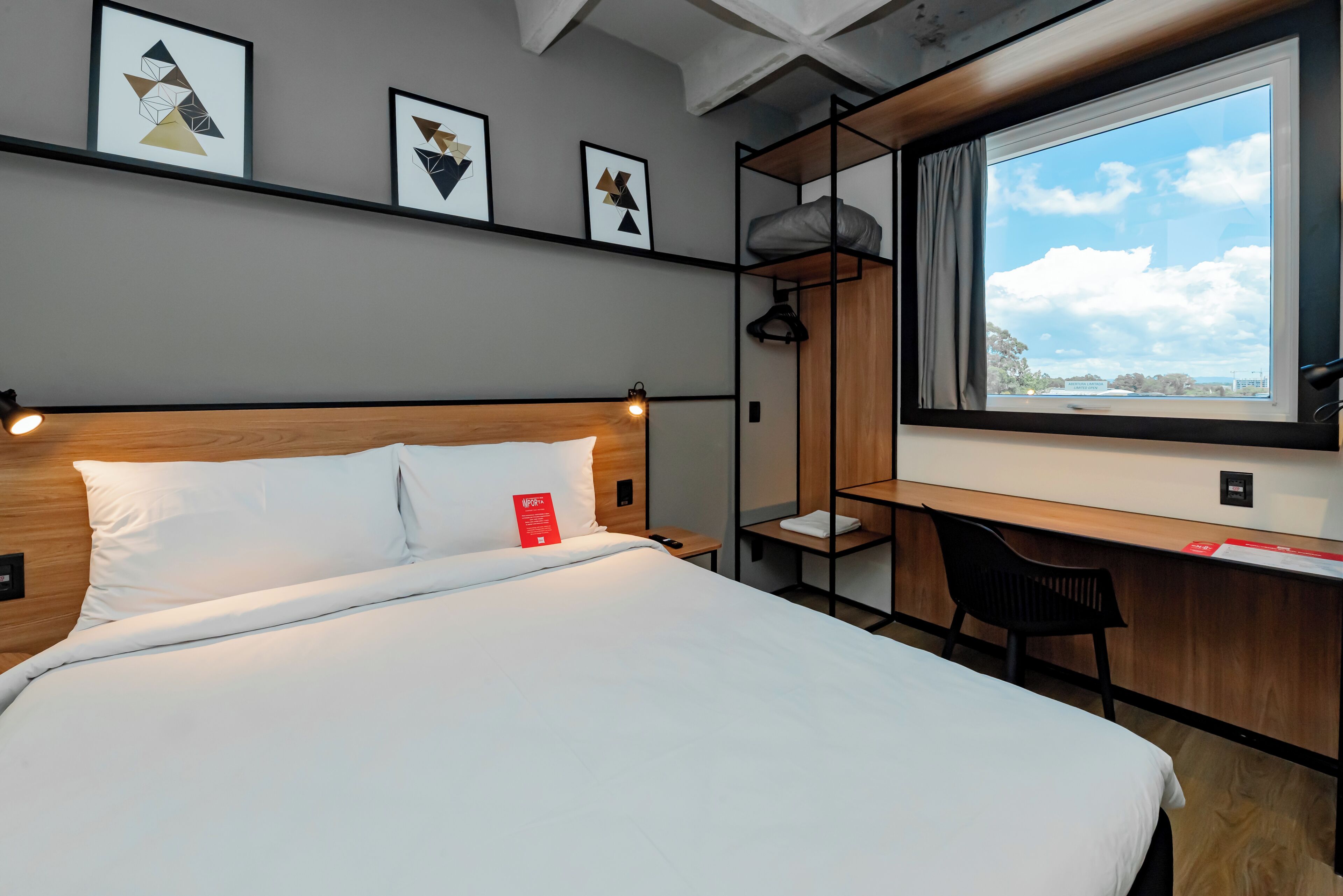 Habitación de hotel con cama, escritorio y ventana con vistas.
