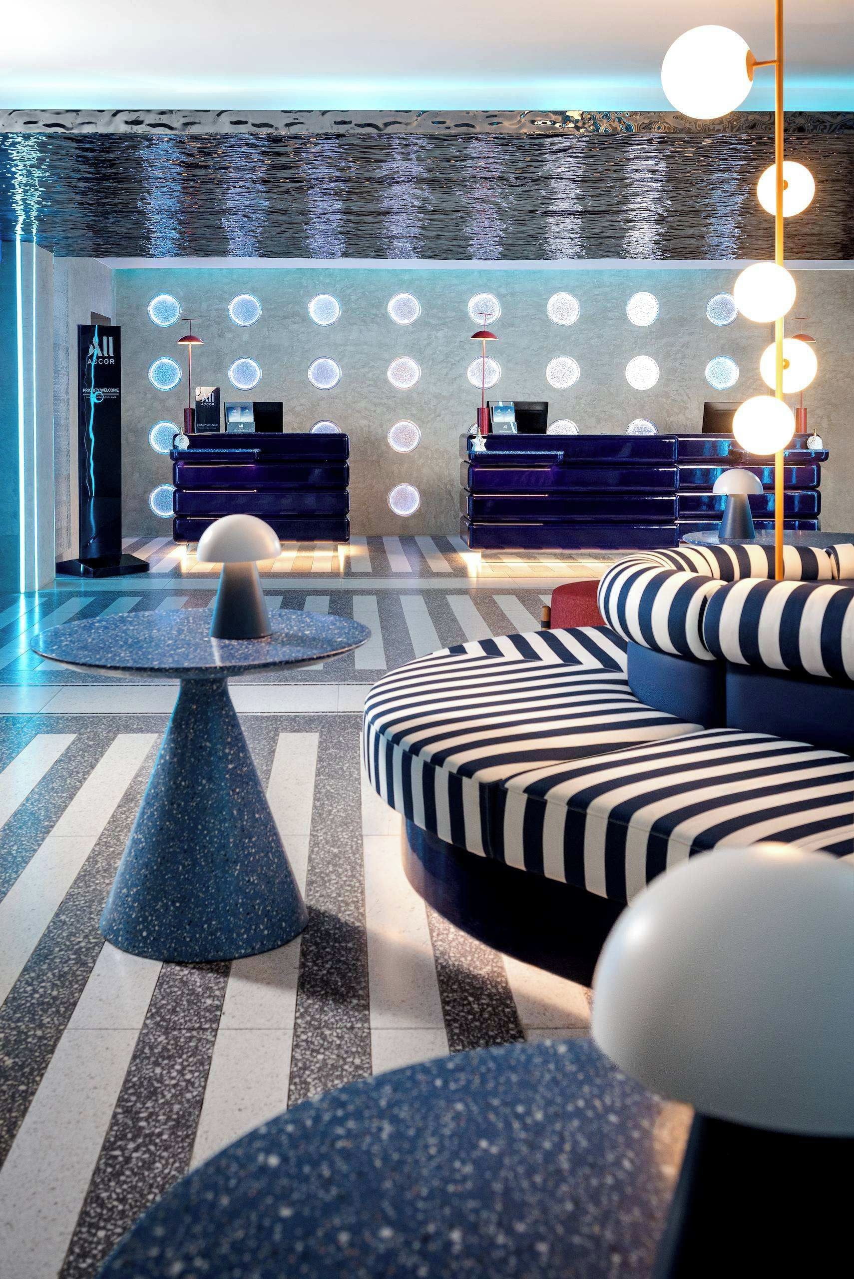 A modern lounge area with a pool, lounge chairs, and a bar area.