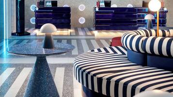 A modern lounge area with a pool, lounge chairs, and a bar area.