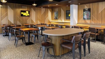A restaurant interior with wooden panel walls, multiple seating arrangements including tables and booths, and hanging pendant lights.