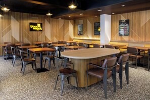 Interior de restaurante con paneles de madera, varios arreglos de asientos que incluyen mesas y cabinas, y lámparas colgantes.