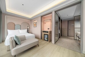 Une chambre d’hôtel moderne équipée d’un lit, d’un canapé, d’une table de chevet et d’un petit réfrigérateur.