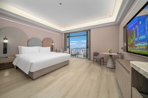 Une chambre d’hôtel moderne, dotée d’un grand lit, d’un bureau et offrant une vue sur la ville.