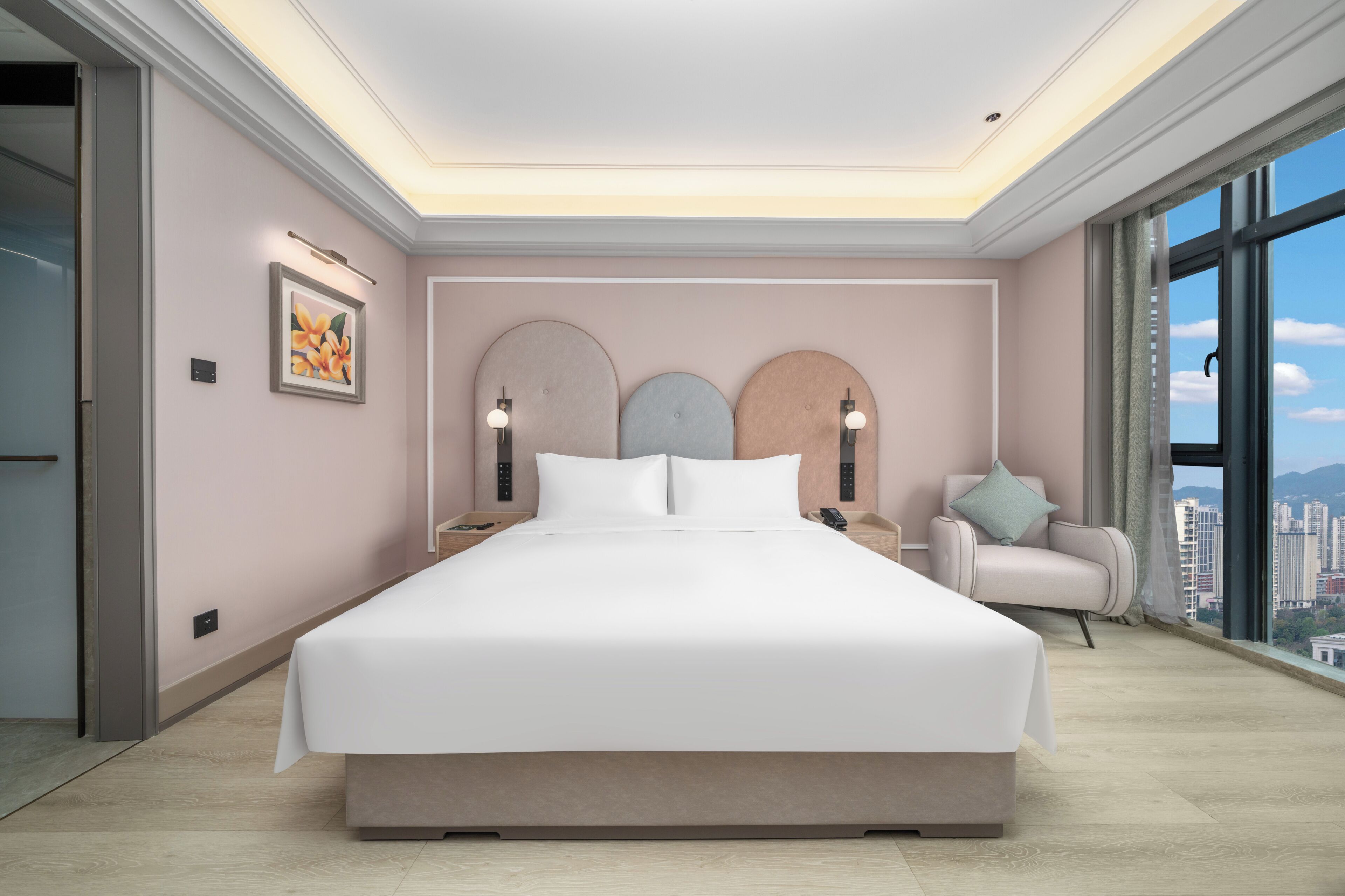 Un dormitorio moderno con una cama grande, mesitas de noche, una silla y vistas a la ciudad.