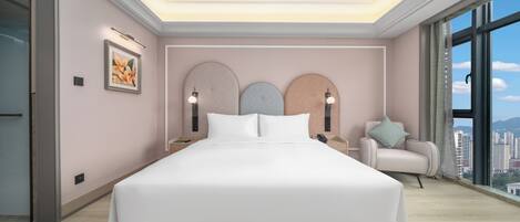 Un dormitorio moderno con una cama grande, mesitas de noche, una silla y vistas a la ciudad.