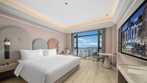 A modern hotel room with a large bed, a desk, a chair, a TV, and a view of the city. - Mercure Hangzhou Gongshu Wanda Plaza (Hangzhou)