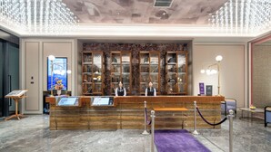 A hotel reception area with a wooden reception desk, marble flooring, and a ceiling with a unique light fixture. - Mercure Hangzhou Gongshu Wanda Plaza (Hangzhou)