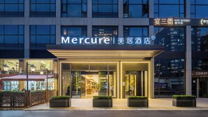 A modern hotel entrance with a prominent sign, glass doors, and a well-lit facade. - Mercure Hangzhou Gongshu Wanda Plaza (Hangzhou)