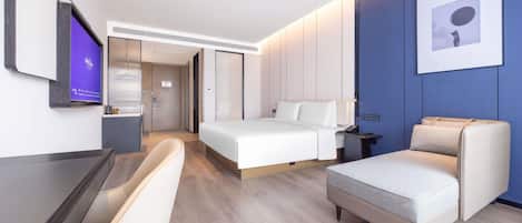 A modern hotel room with a bed, a desk, a chair, and a television.