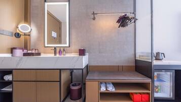 A modern bathroom with a vanity, mirror, towel rack, and a small storage area with shoes.
