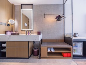 A modern bathroom with a vanity, mirror, towel rack, and a small storage area with shoes.