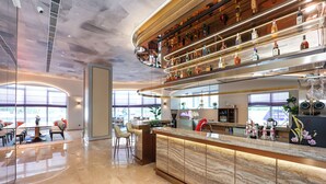 A modern bar area with a marble countertop, shelves of liquor bottles, and a seating area with chairs and a table. - Mercure Jinan West Railway Station (Jinan)