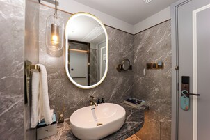 Un baño moderno con un lavamanos de mármol, un espejo grande con marco dorado y un perchero para toallas.