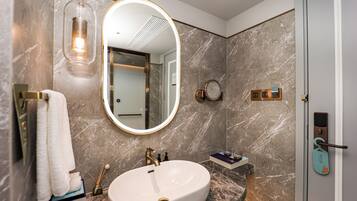 A bathroom with a marble sink, a large mirror, a towel rack, and a door with a keycard lock.