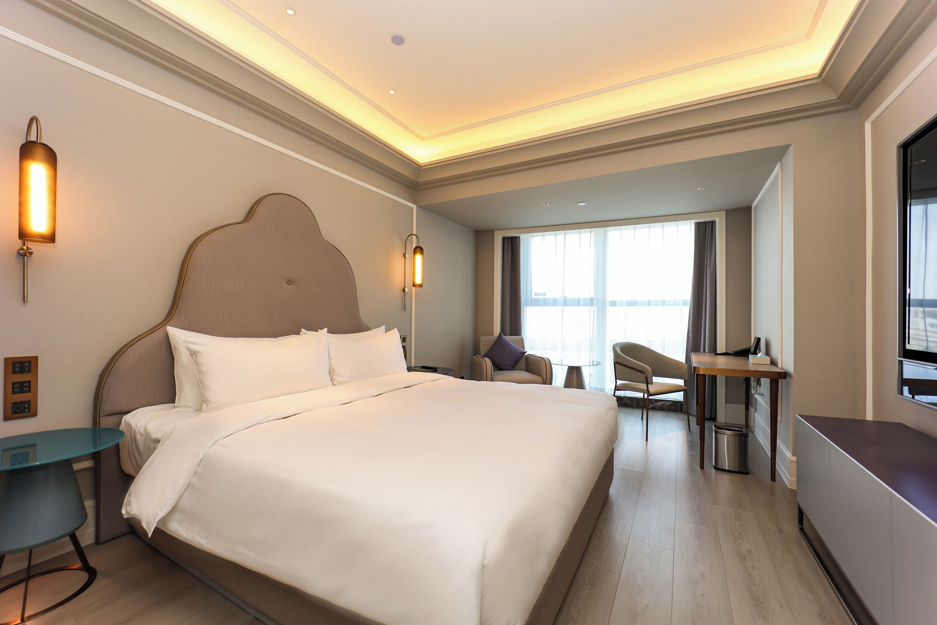 Una habitación de hotel con una cama grande, mesitas de noche, un escritorio y una silla.