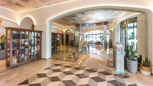 A spacious lobby with a geometric tile floor, a glass display case with books, and a seating area with chairs and tables. - Mercure Jinan West Railway Station (Jinan)