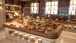 A buffet with various food items and a marble wall with wine bottles. - Mercure Jinan West Railway Station (Jinan)