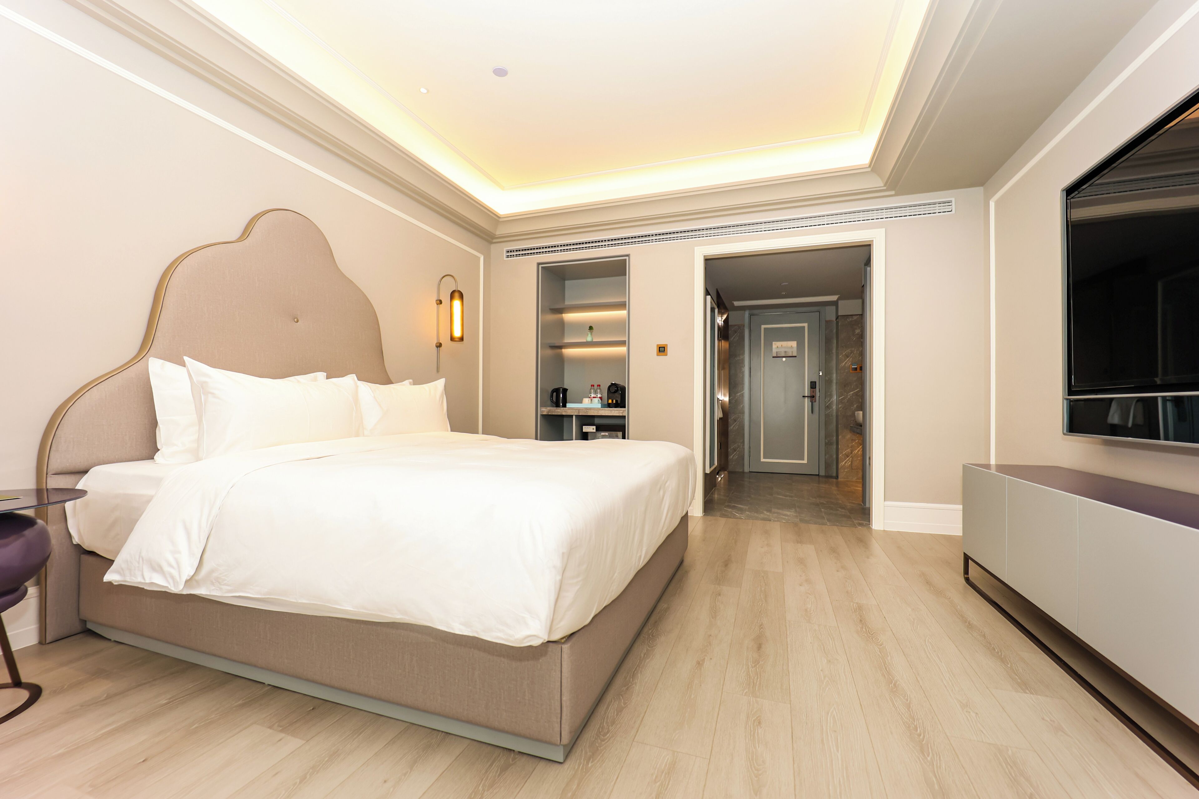 Une chambre d’hôtel moderne dotée d’un grand lit, d’une télévision, d’un bureau et d’un dressing.