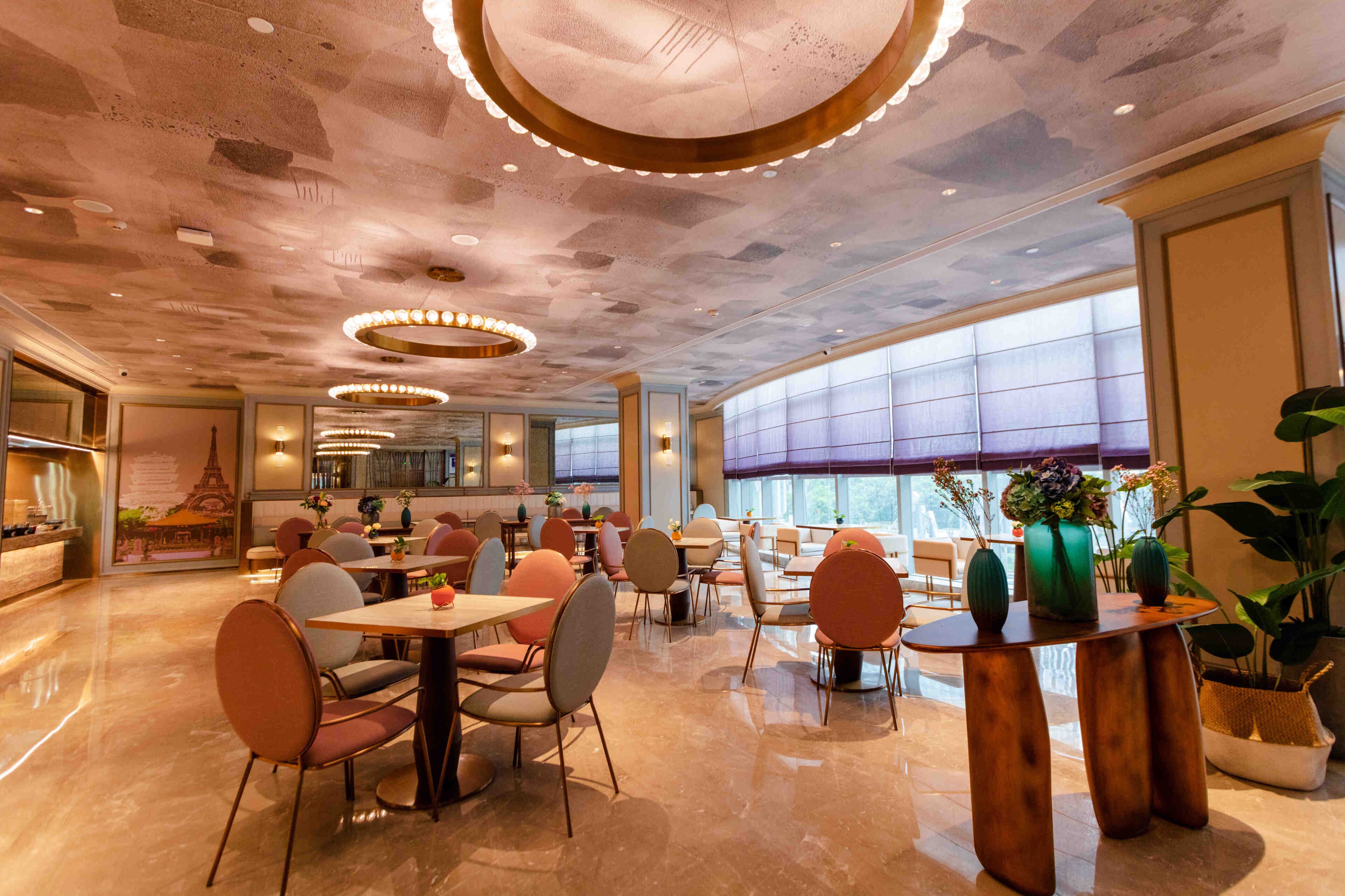 A spacious restaurant with high ceilings, modern lighting, and large windows.