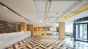 A modern hotel lobby with a reception desk, seating area, and a view of the outdoors. - Mercure Shanghai Pudong Zhangjiang Park (Shanghai)