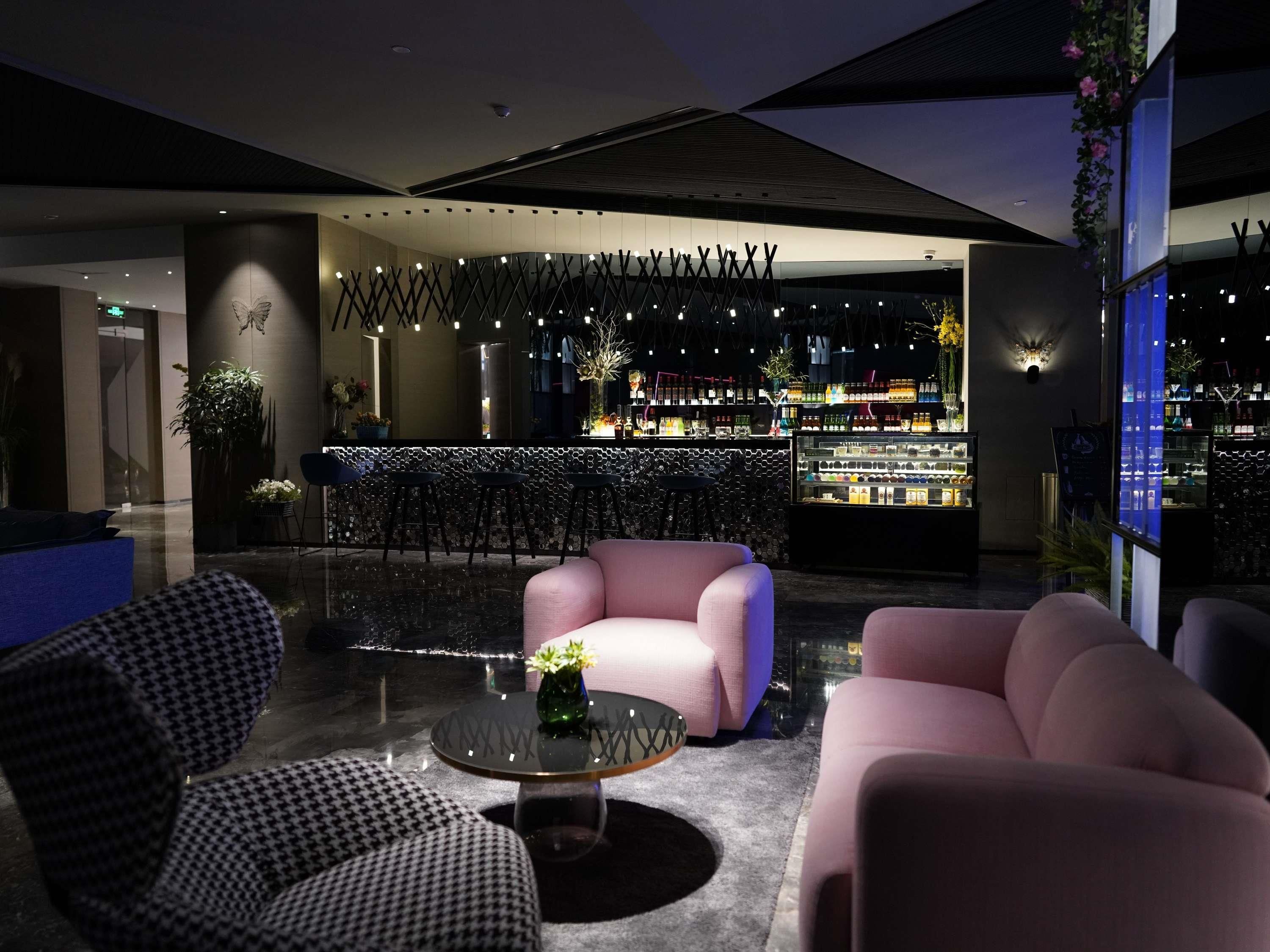Un vestíbul modern amb zona de bar, espais d'seure i una paret decorativa.