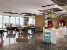 A modern restaurant with a marble floor, large windows, and a view of the city.