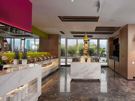 A modern hotel lobby with a reception desk, seating area, and a view of the outdoors.