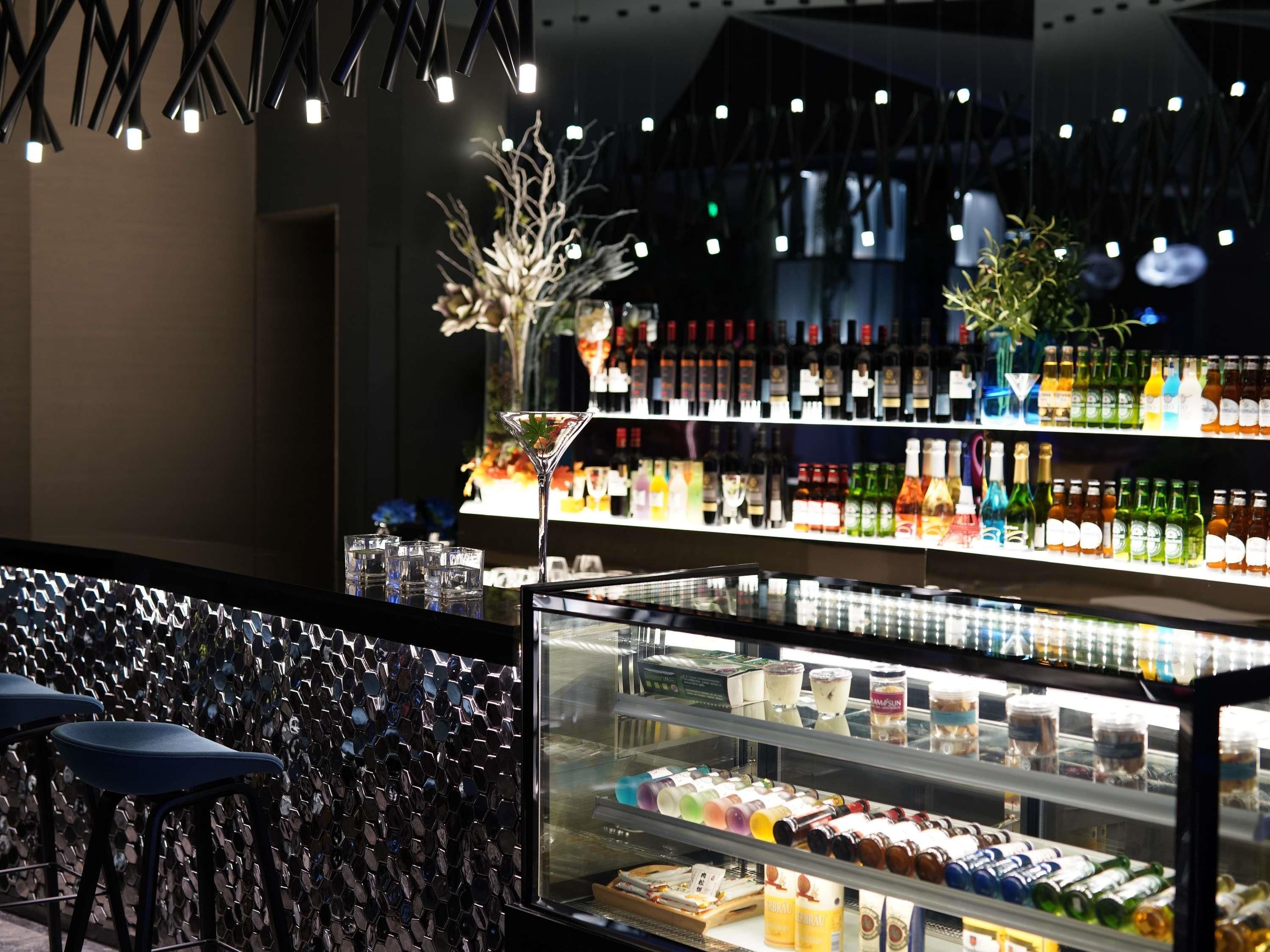 A bar area with a glass display case containing various bottles and a shelf with bottles behind it.