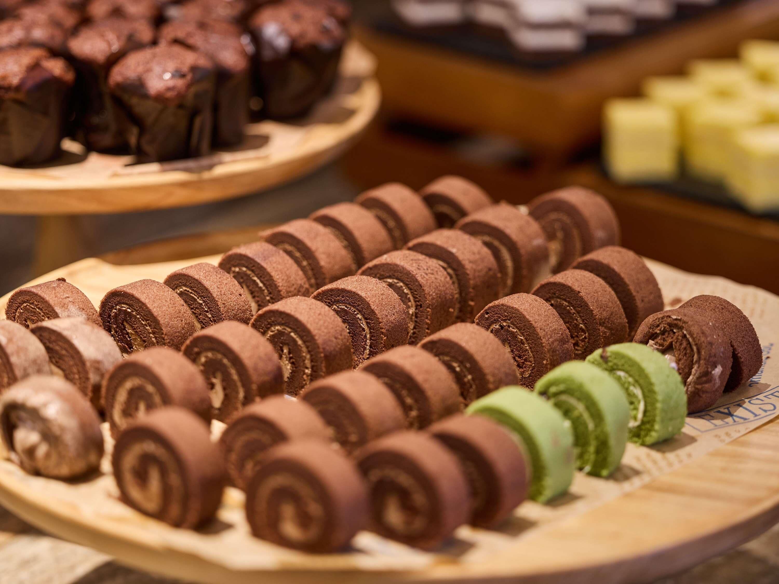 A display of chocolate rolls and other baked goods on wooden trays.